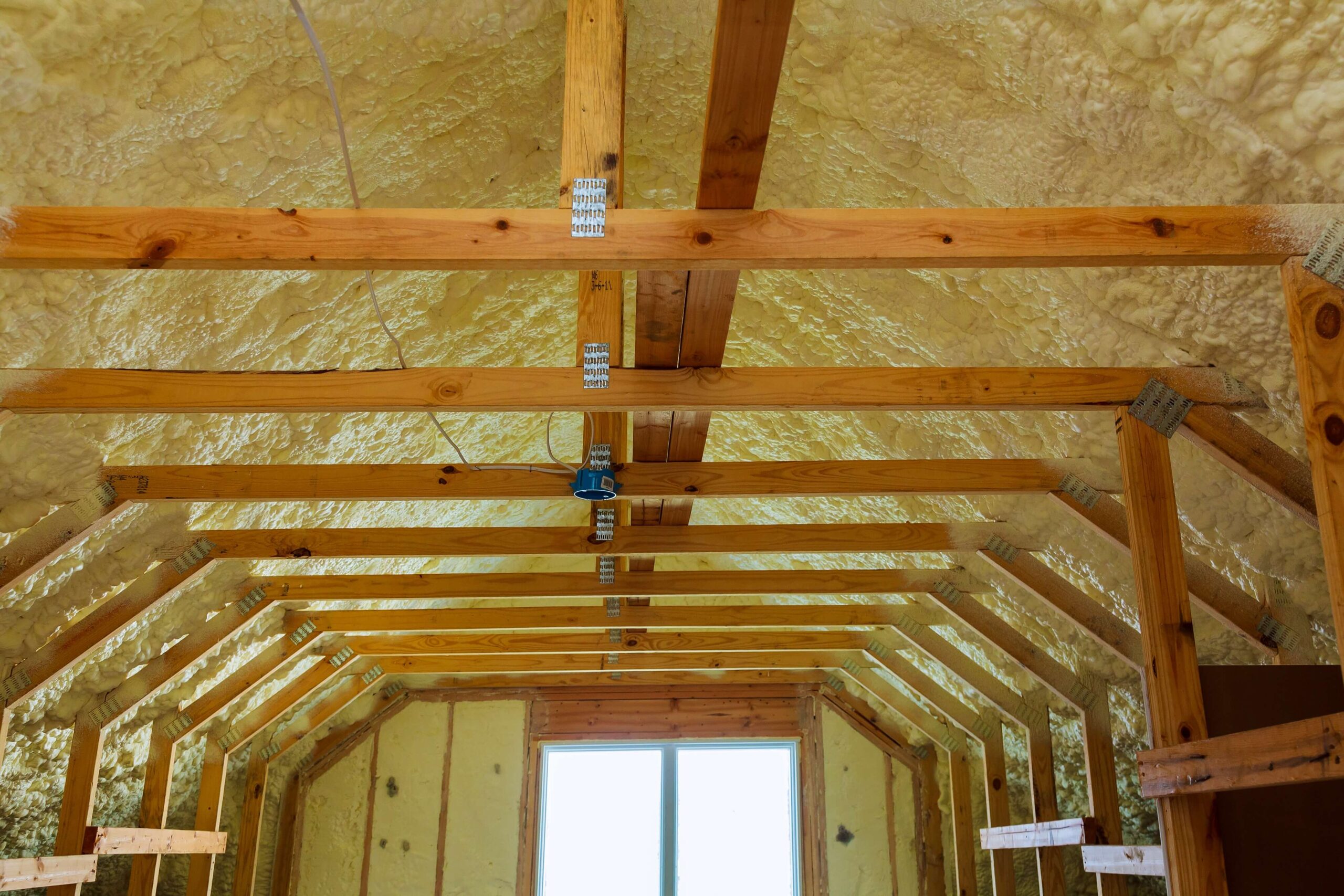 The inside of an attic with wood beams and insulation.