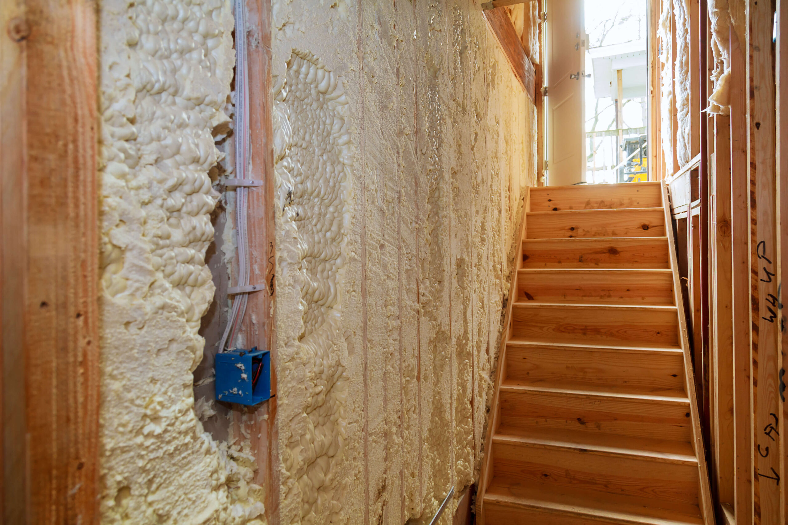 Interior view of a building under construction in El Paso, Texas, showcasing a staircase and walls insulated with spray foam.