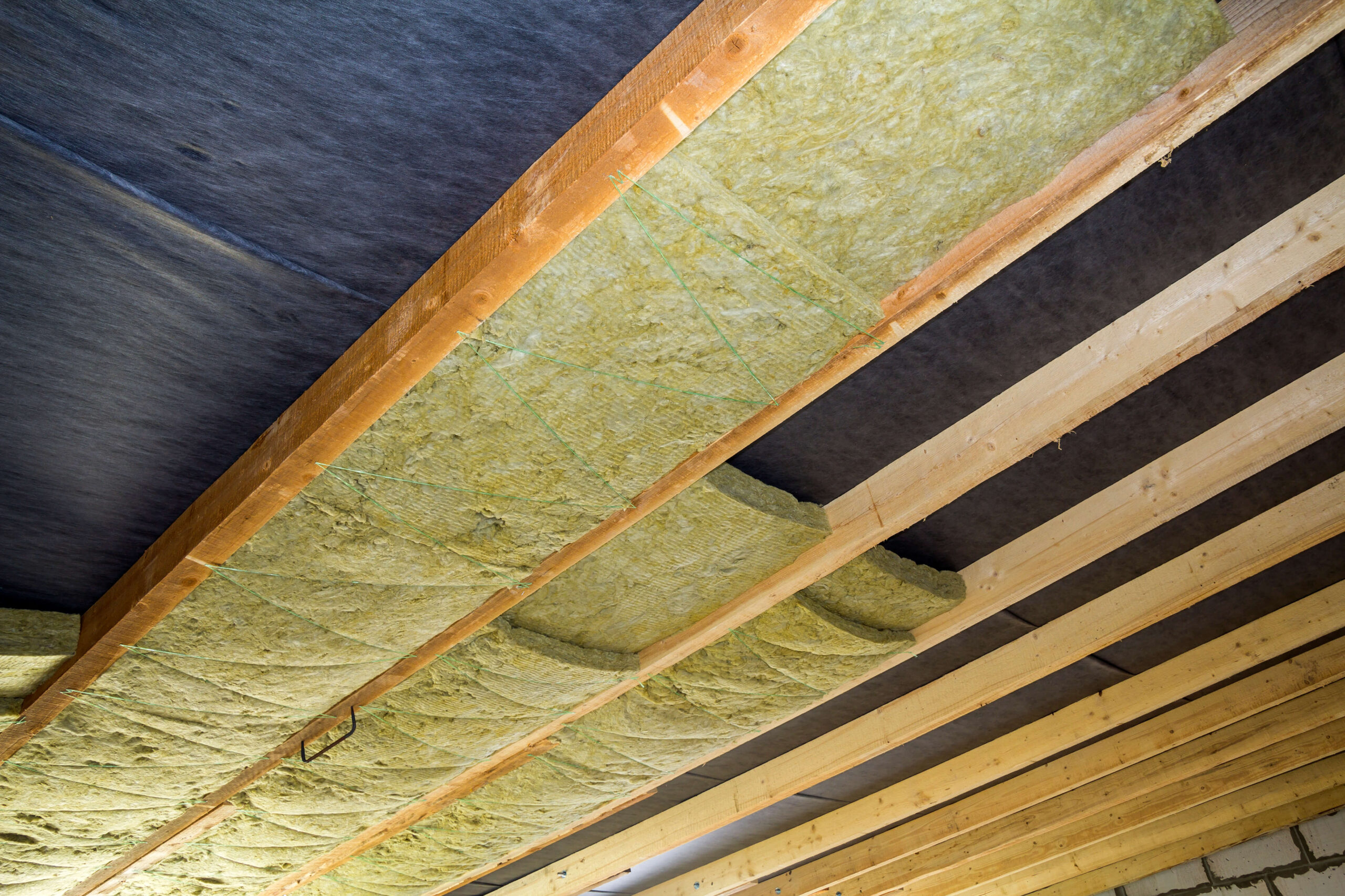 A room with wood beams and insulation in the ceiling.