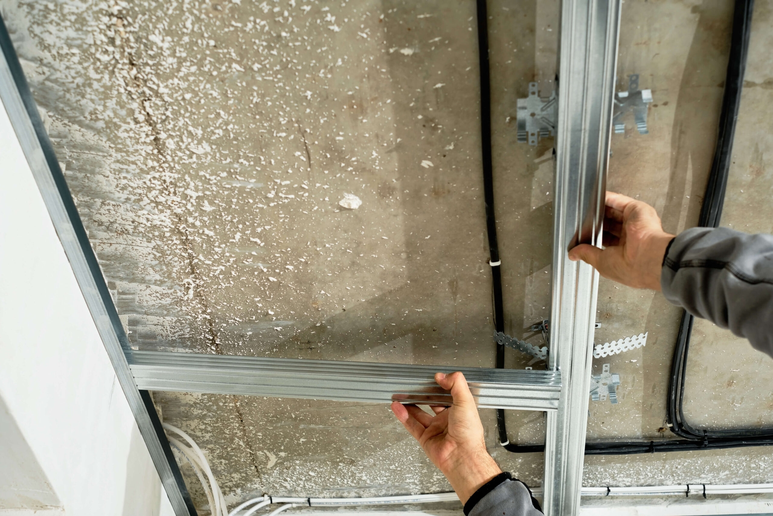 A man is holding up a metal frame in a garage.